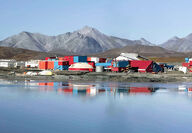 Red, white, blue buildings reflect off pond at Red Dog zinc mine in Alaska.