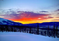 A bright orange sunset over the mountains in Yukon, Canada.
