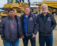 Alaska Native Village chief and mining executives in front of a Cat dozer.