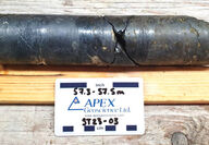 An 8-inch section of gunmetal-colored drill core that is roughly 50% copper.