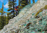 A geologist examines a slope riddled with copper mineralization.