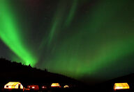 The northern lights shine brilliant green above an exploration camp.