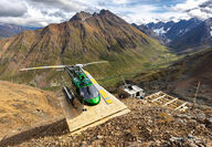 A helicopter sits on a drill pad on a highly mineralized mountain in the Yukon.