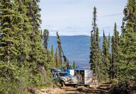 Truck parked next to drill pad on rough road in Yukon wilderness.