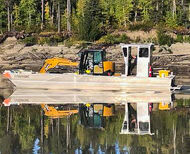 An excavator being barged across the Liard River in Northwest Territories.