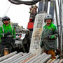 Drillers in grease-covered raingear give a thumbs up at the Arctic Mine project.