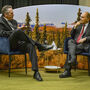 Alaska governor and energy analyst sitting in front of Alaska landscape photo.