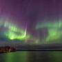 Curtains of green and purple northern lights reflect off lake in NWT.