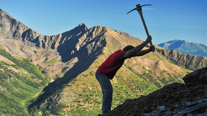 A geologist swings a pickaxe on a slope in the Selwyn Basin in Yukon, Canada.