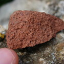 A small chunk of reddish-brown raw bauxite before it is processed into alumina.