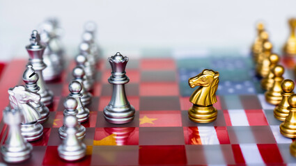 A U.S. versus China chess board with metallic gold and silver pieces.