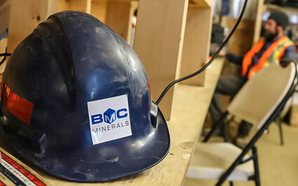 A blue hardhat with the BMC Minerals logo sits on shelf at the ABM Mine camp.