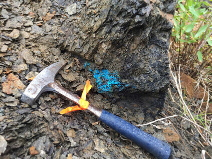 A rock hammer lies next to copper-rich blue mineralization at Galore Creek, BC.