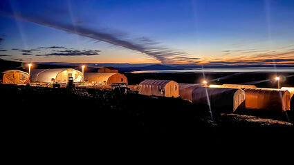 A colorful sunset backdrops a graphite exploration camp in Alaska.