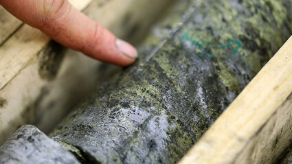 Closeup of a finger pointing to high-grade mineralization in Arctic drill core.