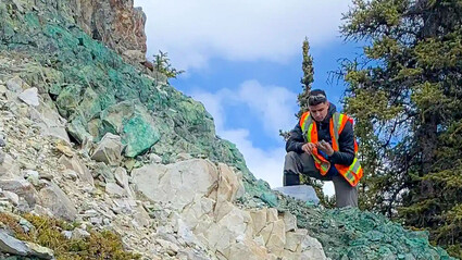 Gladiator geologist inspecting highly mineralized surface copper.