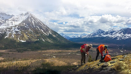 Geologists inspect a hill in the foreground of the beautiful Yukon wilderness.