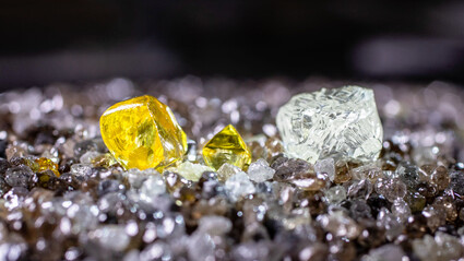 Large yellow and white diamonds on a pile of smaller uncut stones.