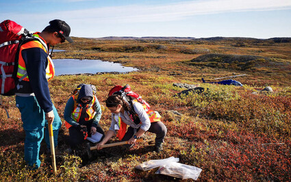 Geologists collect a soil and rock sample below the tundra in Nunavut.