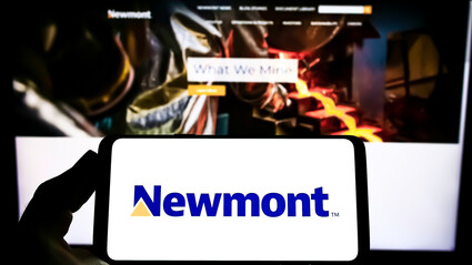 A smartphone displays Newmont’s logo in front of mining company’s webpage.