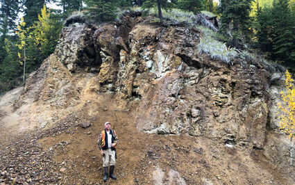 Palladium One VP Exploration Neil Pettigrew standing below rocky outcrop.
