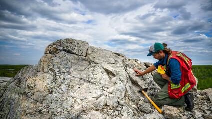 Li-FT geologist examines a large, exposed outcrop at Yellowknife Lithium.