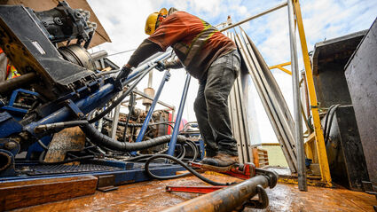 A geologist overlooks the drilling equipment from inside a drill rig.