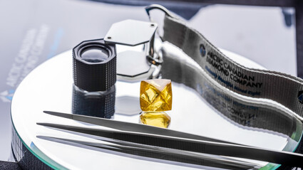 A 71.3-carat yellow diamond with a gemologist loupe and tweezers.