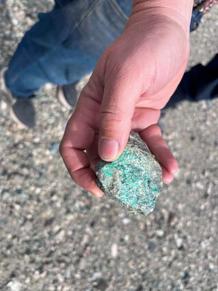 Hand holding a highly copper mineralization grab sample.