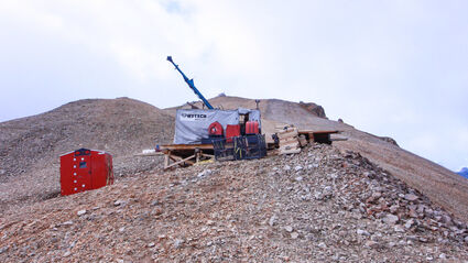 A drill atop a rocky ridge tests the Johnson Tract gold project in Alaska.