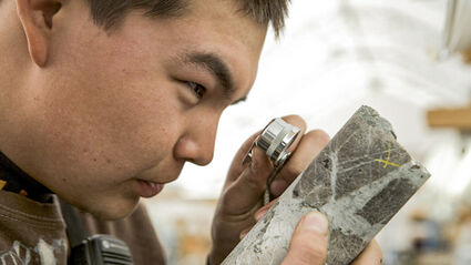 A Pebble mine geologist inspects core using a loupe.