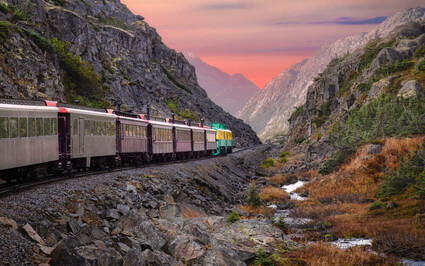 A train passes along a river and fireweed on the White Pass and Yukon Route.