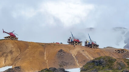 Helicopter atop ridge next to drill rigs testing the Ellis gold zone in Alaska.