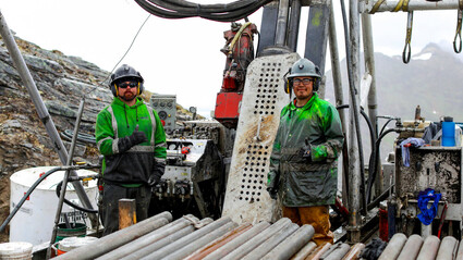 Drillers in grease-covered raingear give a thumbs up at the Arctic Mine project.