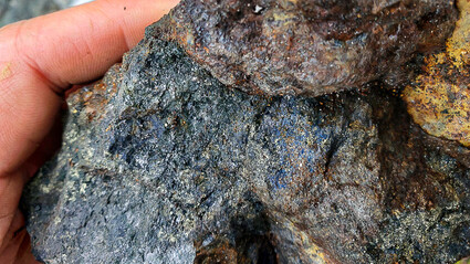 A hand-sized rock sample with extensive blue and gold-copper mineralization.