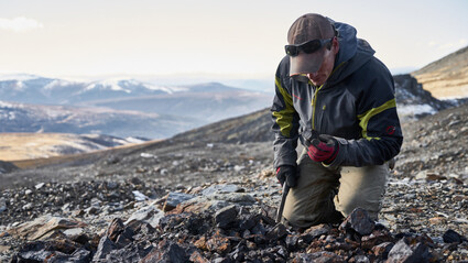 Geologist inspects rocky surroundings at Keno Silver project in Yukon.