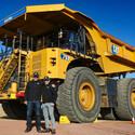 Executives stand in front of an electric Cat mining haul truck.