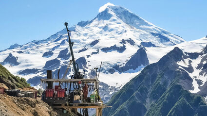 Drill tests for gold before a snowcapped mountain at Johnson Tract in Alaska.